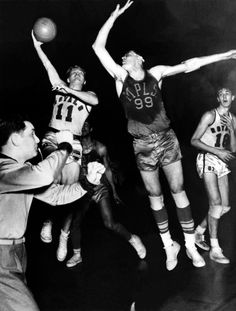 an old black and white photo of basketball players in mid air with the ball above their head