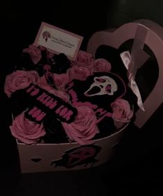 a box filled with pink roses in the shape of a heart and a mask on top