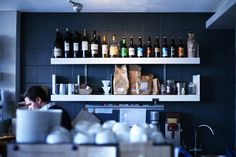 a man working in a kitchen with lots of bottles on the wall and shelves above him