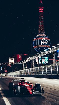 a race car driving down the road in front of a tall building with lights on it