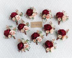 a bunch of red and pink flowers are arranged on a white tablecloth with a name tag