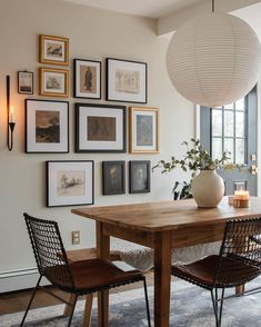 a dining room table with chairs and pictures on the wall