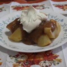 a white plate topped with fruit covered in whipped cream on top of a floral table cloth