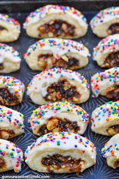 several pastries with white frosting and colorful sprinkles on a tray