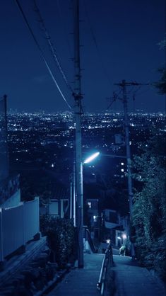 an alley way at night with street lights and power lines above the cityscape