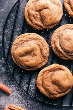 chocolate chip cookies cooling on a wire rack with cinnamon sticks and powdered sugar next to them