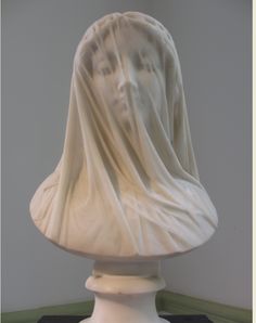 a white statue with a veil on it's head sitting on top of a table