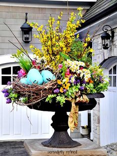 a bird's nest filled with eggs sitting on top of a pedestal in front of a house