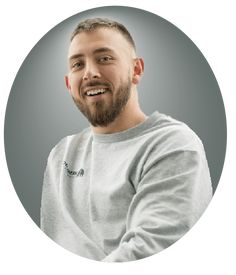 a man with a goatee smiles in a circular photo on a gray background,