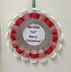 a christmas wreath hanging on the wall with red and white spools attached to it