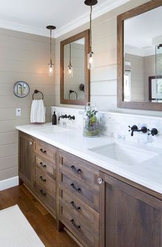 a bathroom with two sinks, mirrors and lights on the wall above them is shown