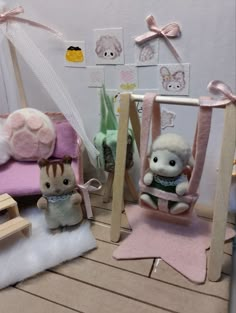 two small stuffed animals sitting on top of a wooden floor next to a doll house