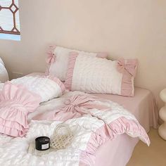 a bed with pink ruffled sheets and pillows