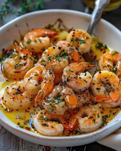 a white bowl filled with cooked shrimp and garnished with herbs