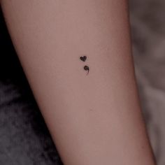 a small black heart tattoo on the arm