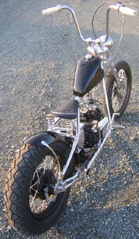 a black motorcycle parked on top of a gravel road