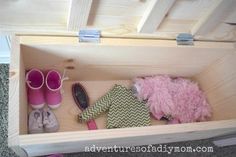 a wooden box filled with pink and green items on top of carpeted flooring