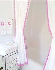 a white bathroom with pink trim on the shower curtain