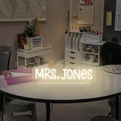 a white table topped with lots of drawers under a neon sign that reads mrs jones