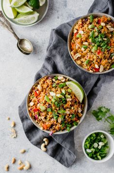 three bowls filled with rice and vegetables on top of a cloth next to silver spoons