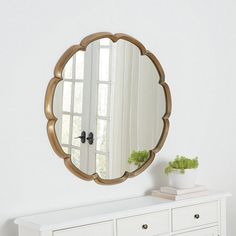 a white dresser with a mirror on top of it and a potted plant next to it