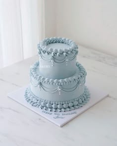 three tiered blue cake sitting on top of a white table