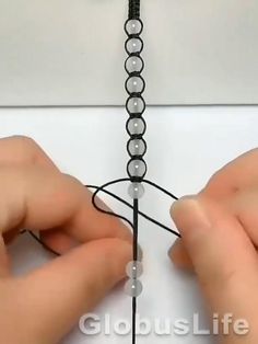 two hands are working on a beaded chain with beads attached to the end of each strand