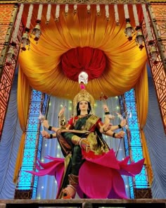 a woman is dancing on stage in front of a large red and yellow curtain with lights