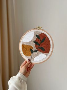 a woman holding up a hand embroidered orange flower