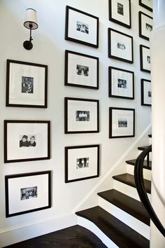 black and white photo frames on the wall next to stairs