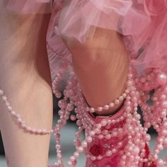 a woman's feet in pink shoes with pearls on them