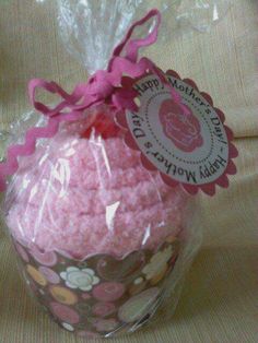 a pink cupcake wrapped in plastic and sitting on top of a table next to a bag