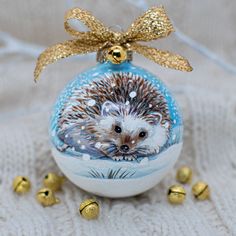 an ornament shaped like a hedgehog on a white blanket with gold bells