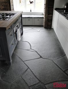 a kitchen with black stone flooring and white cabinets in the back drop down window