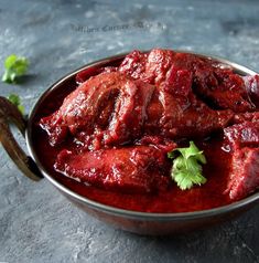 a metal bowl filled with meat covered in sauce