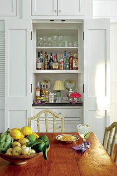 a wooden table topped with plates and bowls filled with food next to white cupboards