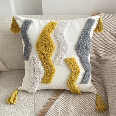 a white couch with a yellow and gray pillow on it