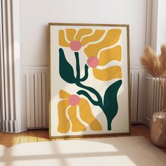 a framed art piece on the floor in front of a radiator and plant