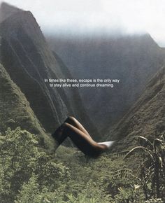 a woman laying down in the grass with her legs spread out and mountains behind her