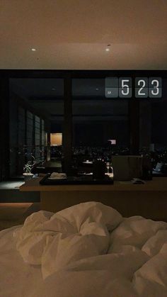 an unmade bed in front of a large window with the number 523 on it