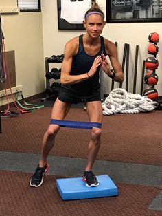 a woman standing on top of a blue block in a gym