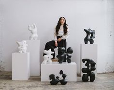 a woman sitting on top of some white blocks next to black and white sculpture pieces