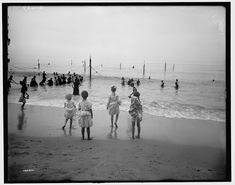 several people are walking on the beach near the water