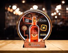 a bottle of booze sitting on top of a wooden table next to a clock