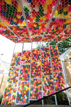 an art installation made out of colored balls and netting on the side of a building