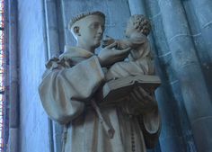 a statue of a man holding a book in front of a stained glass window,