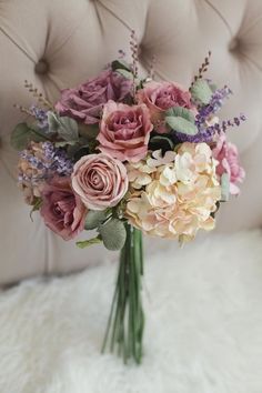 a bouquet of flowers sitting on top of a white furnishing next to a couch