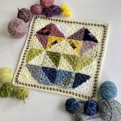 several balls of yarn sitting on top of a table next to a crocheted square