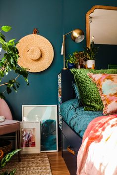 a bedroom with blue walls, green bedding and a plant on the side of the bed