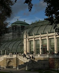 people are walking around in front of a large glass building with many windows and balconies